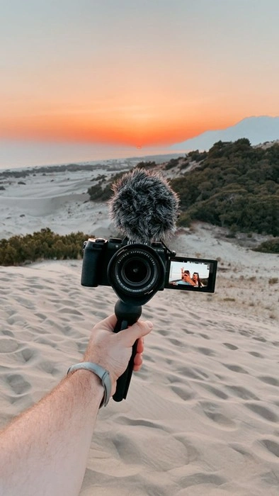 Vlogger filming a desert sunset with mirrorless camera and mic