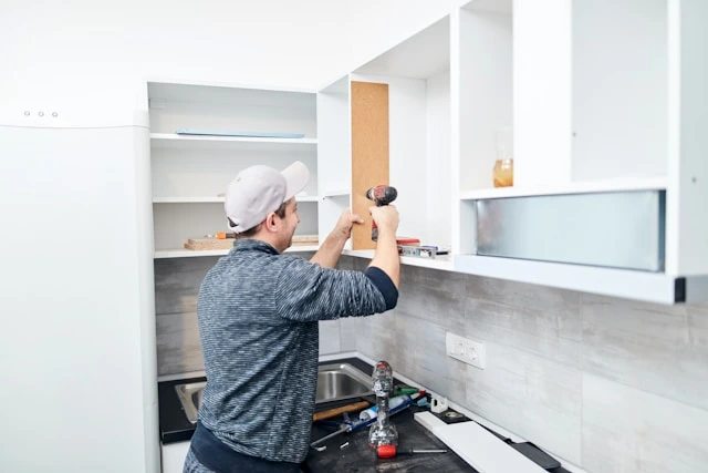 Worker installing new cabinets during a kitchen remodeling project with tools on the counter