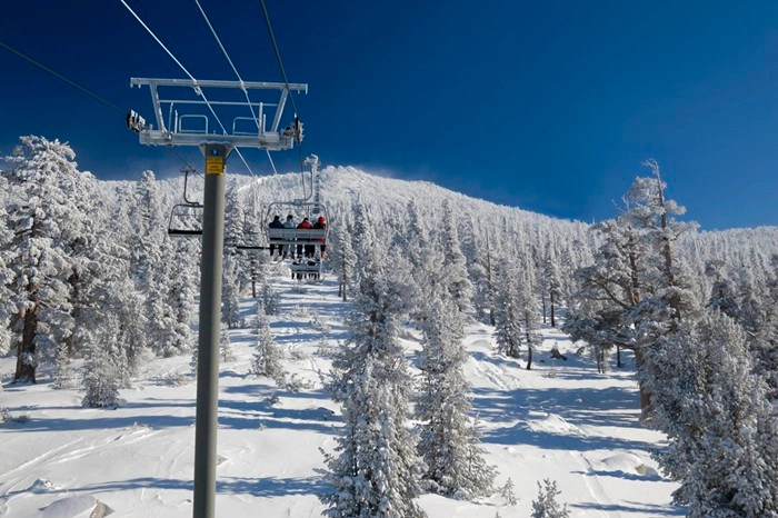 Chairlift carrying skiers through frosted pine trees at Kirkwood ski resort