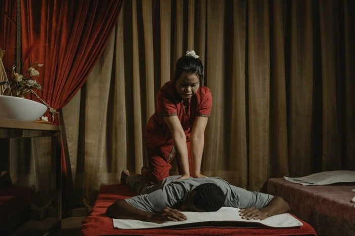 Therapist performing a traditional Thai massage on a client in a dimly lit spa treatment room