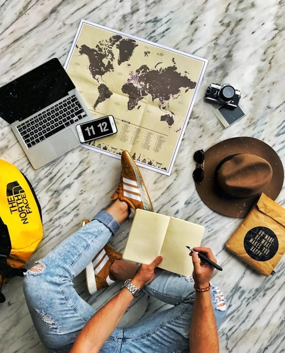 Travel planning flatlay with laptop, world map, and camera