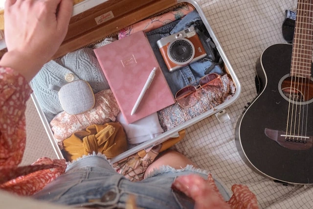 Open suitcase packed with journal, camera, and sunglasses for a solo adventure abroad