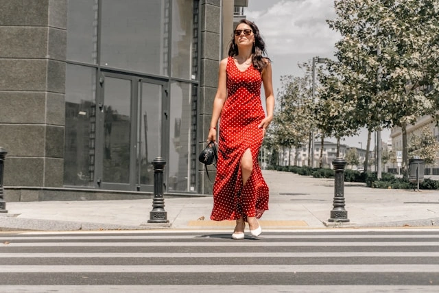 Woman crossing the street in a versatile polka dot dress and white sandals for a casual day look