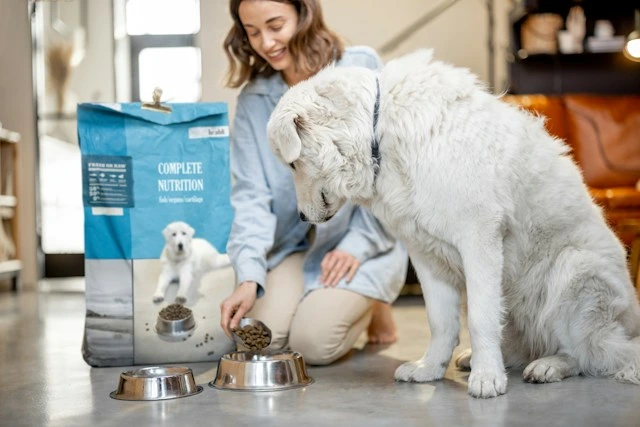 Dog owner pouring kibble from a Complete Nutrition bag into a bowl for her dog