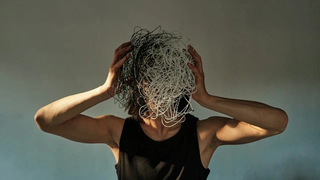Person holding their head wrapped in tangled wire, representing a mind overwhelmed and in need of a mental shift