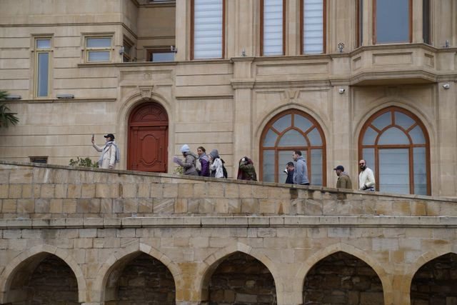 Tour Guide Leading a Group Past a Historic Building's Arched Facade