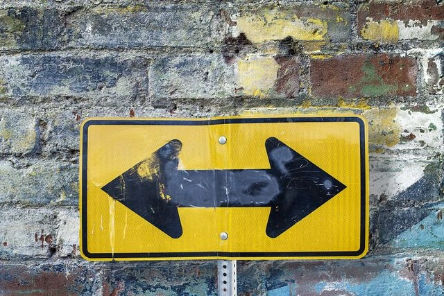 Two-way directional sign on a weathered wall, symbolizing adjustment after a setback