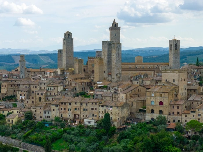 Aerial view of a historic Tuscany hilltop town with medieval stone towers and hotel-lined streets