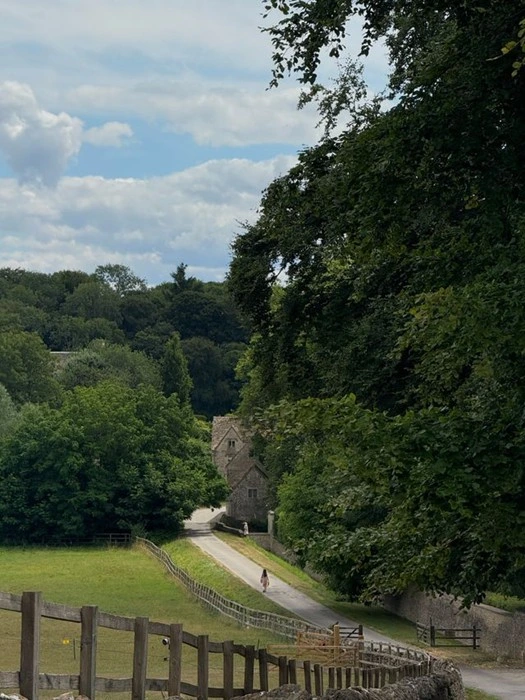 Stone cottage tucked among trees along a quiet lane in Bibury, a picturesque English countryside village