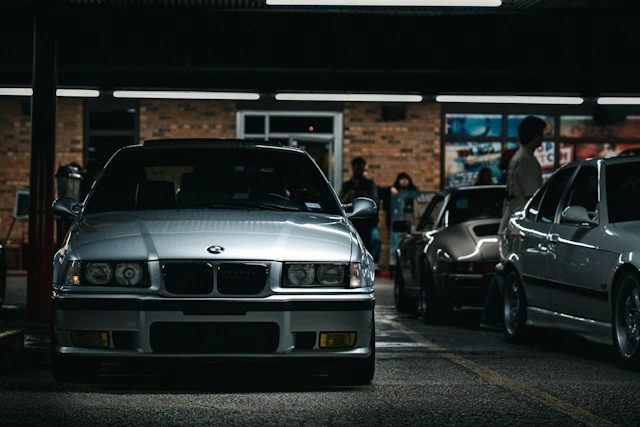 Silver BMW 3 Series parked at night, its metallic body paint catching the overhead lights