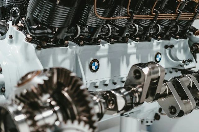 Exposed BMW engine with finned cylinders, a crankshaft, and gears on a white engine block