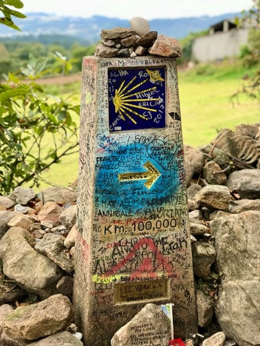 Stone Camino de Santiago milestone marker covered with pilgrim signatures and messages
