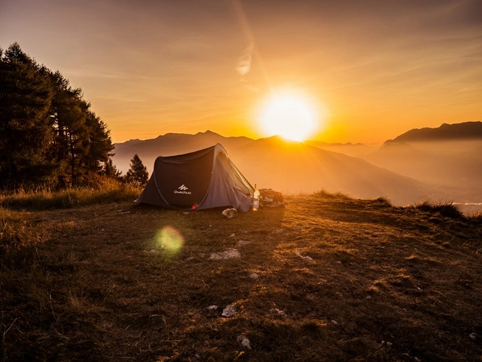 Camping tent pitched on mountain ridge at sunset
