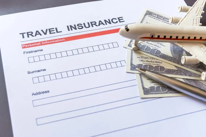 A blank travel insurance claim form with a pen, $100 bills and a model airplane, ready for a cancelled flight claim