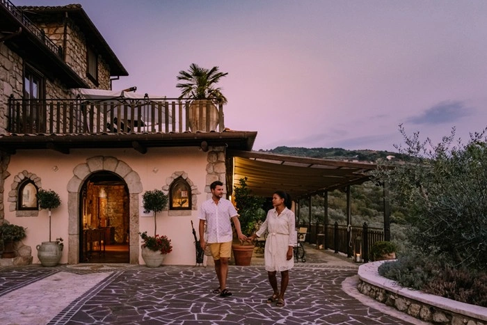 Couple walking outside a luxury hotel in Tuscany at dusk with stone architecture and olive trees