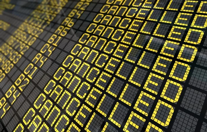 Airport departure board showing a flight cancelled in Canada, with yellow "Cancelled" displayed on every row beside the gate numbers