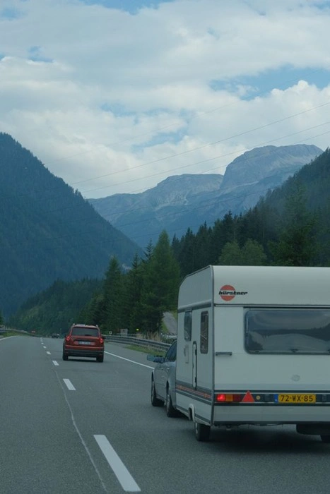 Europe by caravan road trip through a scenic mountain pass with towering peaks