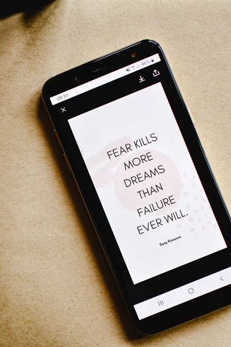 Smartphone displaying quote 'Fear kills more dreams than failure ever will' about overcoming setbacks