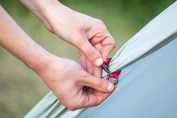 Hands fixing a tent zipper pull while camping