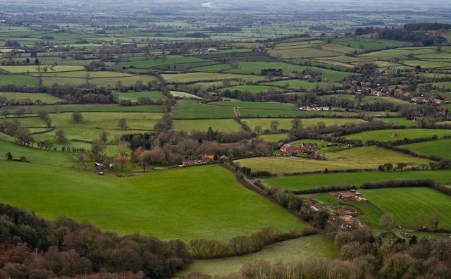 Aerial view of patchwork green farmland and villages across the English countryside