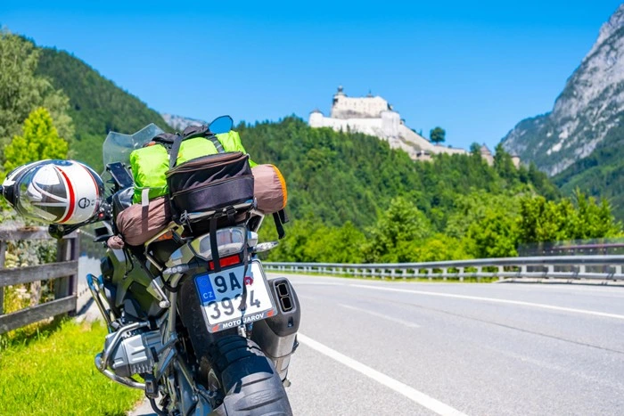 Europe by motorbike — fully packed motorcycle parked with mountain castle view