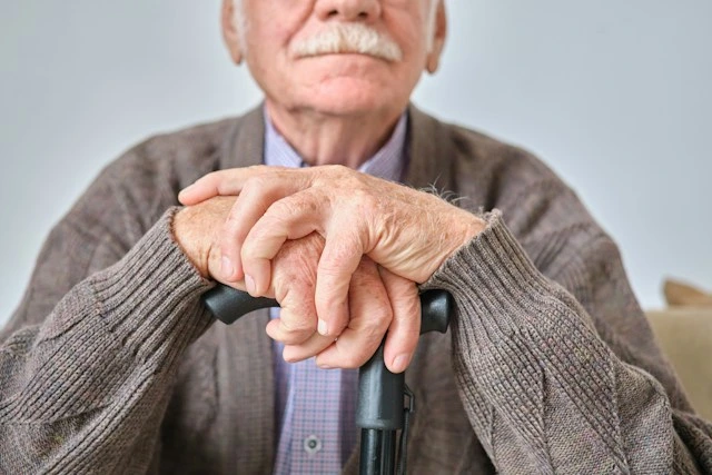 Elderly man resting his hands on a cane in a nursing home