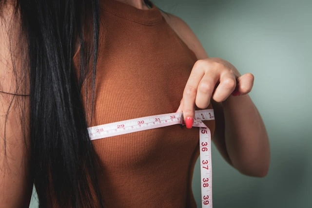 Woman measuring her chest with a tape measure to track body progress