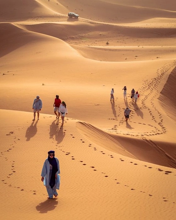 Local Guide Leading a Group Across Desert Dunes on a Guided Tour