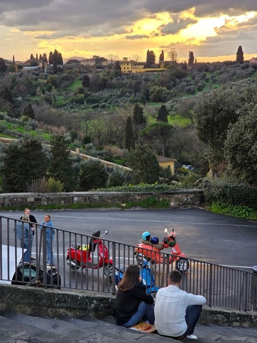Travelers parked on scooters overlooking Tuscany hills at sunset