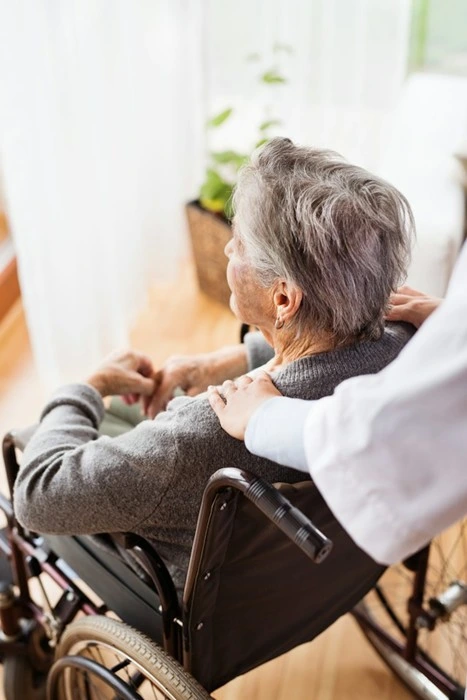 Elderly woman in a wheelchair being comforted by a caregiver