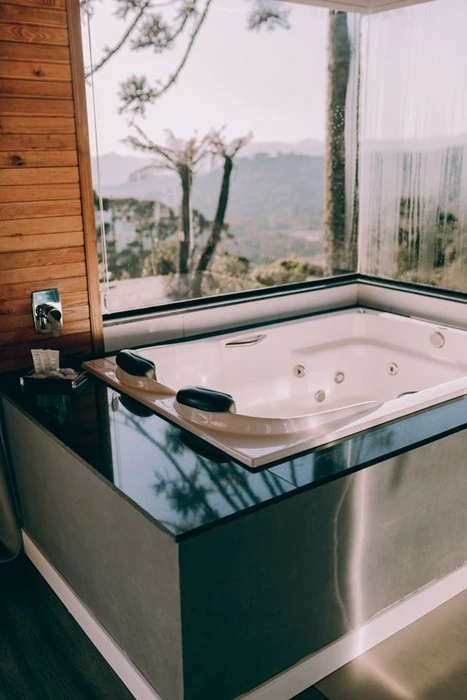 Spa hotel jacuzzi tub with floor-to-ceiling windows overlooking misty hills, a relaxing retreat for countryside travelers