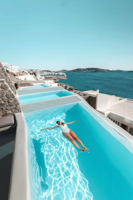 Why luxury travel is worth it — infinity pool overlooking Mykonos coastline with cliffside villas