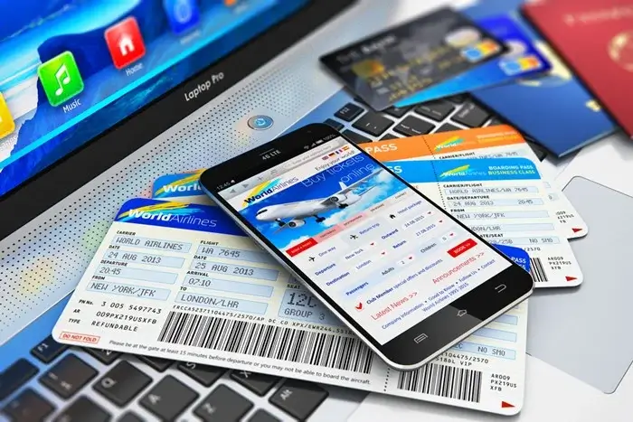 Smartphone showing a flight booking page on top of printed boarding passes, credit cards and a passport on a laptop keyboard for an onward visa ticket service review