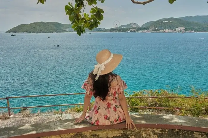 Woman in a straw hat sitting by the turquoise waters of Nha Trang Bay, a popular coastal spot to visit in Vietnam