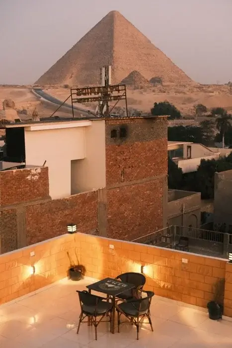 Rooftop terrace with a table for two at dusk, overlooking the Great Pyramid of Giza and the Sphinx in Egypt