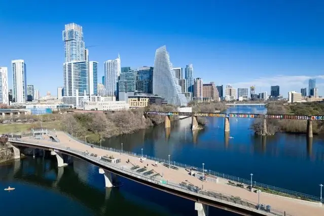 Downtown Austin, TX skyline over Lady Bird Lake, with a pedestrian bridge and graffiti-covered rail bridge in the foreground