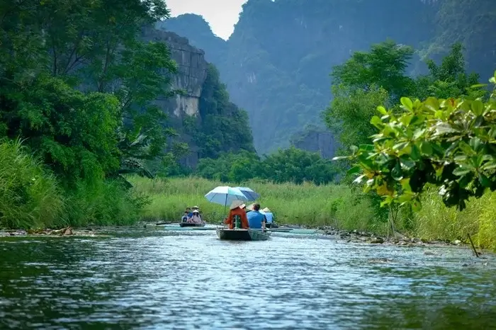 Boat ride through green riverbanks and towering karst mountains in Ninh Binh, northern Vietnam
