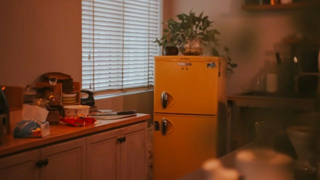 Dim home kitchen with a yellow fridge and cluttered counter, showing tips for checking appliances after a long power outage