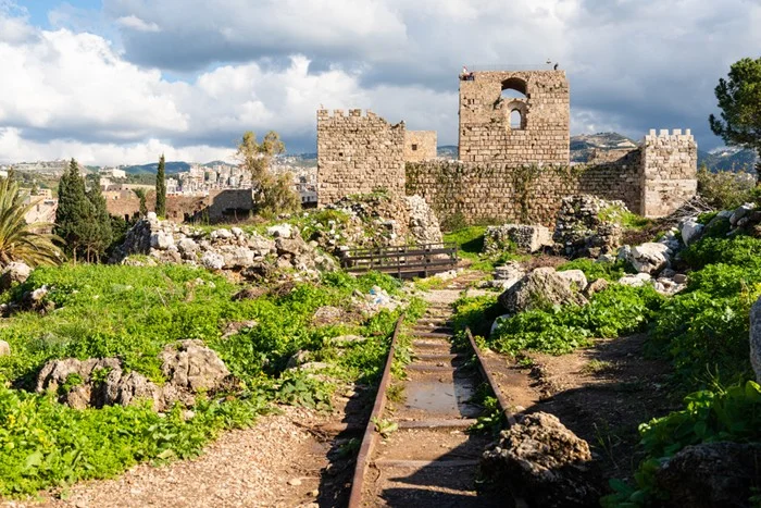 Crusader castle ruins at the Byblos archaeological site in Lebanon, a popular day trip from Beirut, with a stone path through green grass