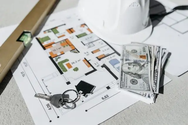 House floor plan with $100 bills, keys, a level, and a white hard hat, showing what’s at stake in contractor invoicing