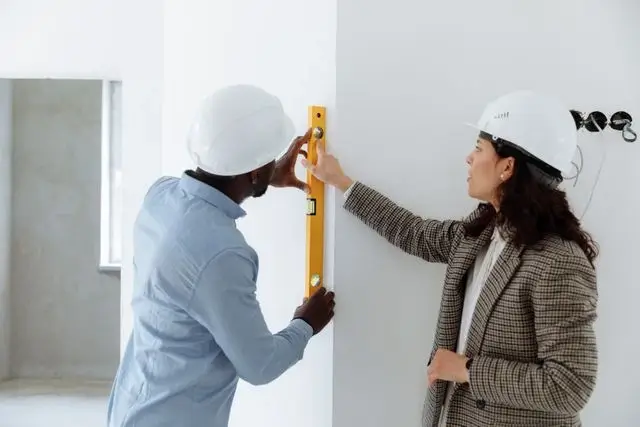 Construction professionals using a spirit level to confirm the work is done right before billing the client