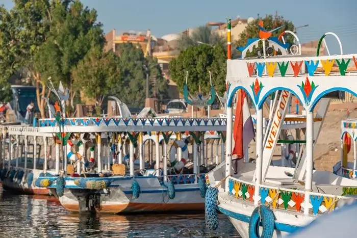 Colorful traditional Nile boats painted with bright Nubian-style patterns, moored along the riverbank in Egypt