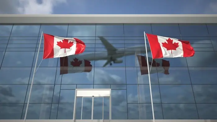 Canadian flags waving outside an airport terminal as a plane flies overhead, a reminder that Canada’s eTA covers air travel for Indonesia and Malaysia passport holders