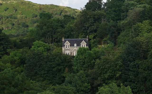 Stone house tucked into a dense wooded slope, a reminder of why hillside home tips for disaster recovery matter