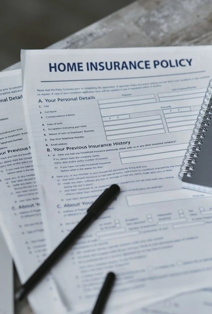 Home insurance policy forms and a pen on a table, ready for reviewing ALE coverage before a hillside disaster