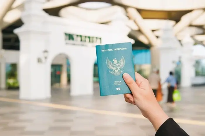 Hand holding an Indonesian passport inside an airport terminal, a key travel document when applying for a Canada eTA from Indonesia