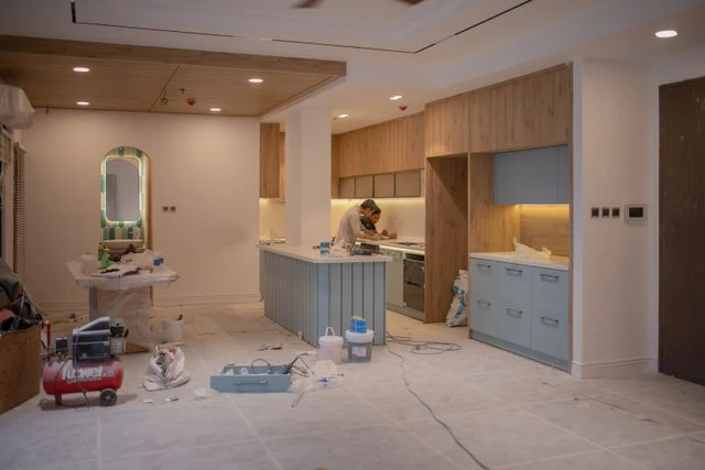 Contractor working on a home kitchen rebuild with tools and supplies spread across the floor, a project that can run past 2 months