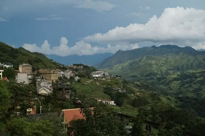 Hillside town of Sapa overlooking green valleys and mountains under dramatic clouds, a scenic place to visit in northern Vietnam