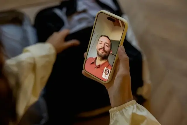 Woman on a video call with her partner while packing a bag, keeping an international relationship going across time zones