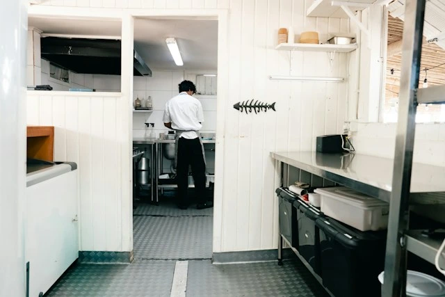Cook working in a compact stainless steel kitchen, similar to a temporary setup that keeps a household fed while the home kitchen is rebuilt
